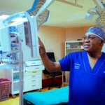 Songabau in his office, discussing women's health with a patient and using an anatomical model of a uterus on his desk to explain a condition.